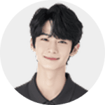 A young person with short, wavy black hair smiles softly at the camera, wearing a dark collared shirt against a plain light background.