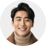 A smiling person with dark hair wearing a brown turtleneck sweater and jacket, shown against a plain light background.